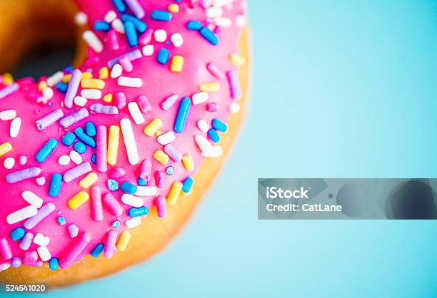 Donut With Pink Icing And Sprinkles On Blue Background Stock Photo - Download Image Now