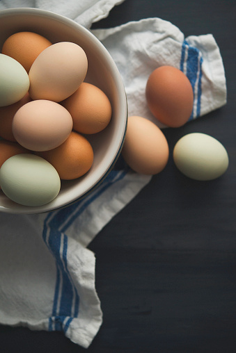 Fresh organic free range eggs in various hues in bowl