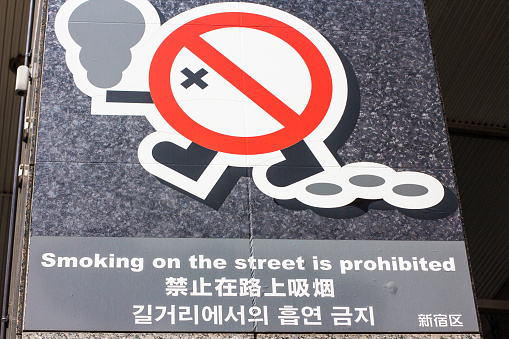 Tokyo, Japan - March 27, 2016: A no smoking sign published on the pavements of Shinjuku in Tokyo. Underneath the no smoking logo is Japanese writing. The English reads: 'Smoking on the street is prohibited'.