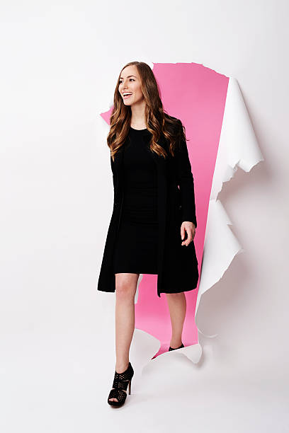 istock Fashion model emerging from torn paper in studio 524554164