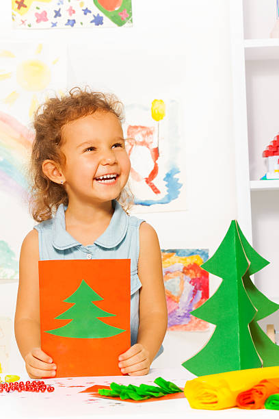 istock Laughing looking girl holds card with Xmas tree 524576073