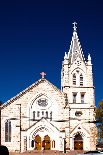 Old historical church facade in Fredericksburg, Texas, USA. Beautiful architecture in this limestone construction. Steeple, spire, crosses on chuch exterior. Outdoors, clear blue sky. Entrance.