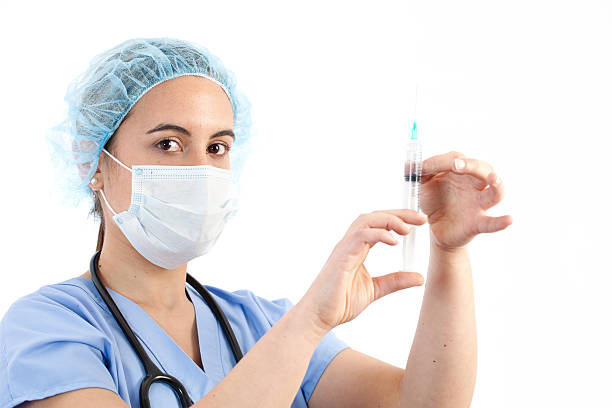 jovem médico feminino segurando uma seringa - syringe medical injection surgical needle surgical mask - fotografias e filmes do acervo