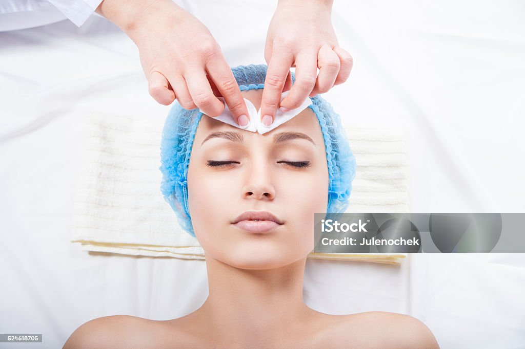 Skin care - woman cleaning face by beautician Skin care - woman cleaning face by beautician over white background Adult Stock Photo