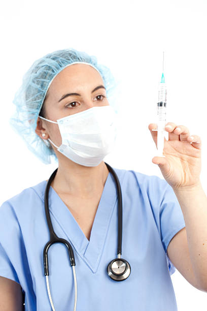 junge ärztin hält eine spritze - syringe medical injection surgical needle surgical mask stock-fotos und bilder