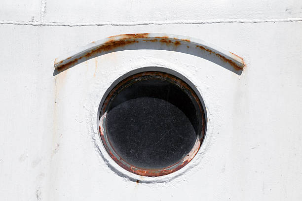 istock Old round porthole on white ship hull 524624377