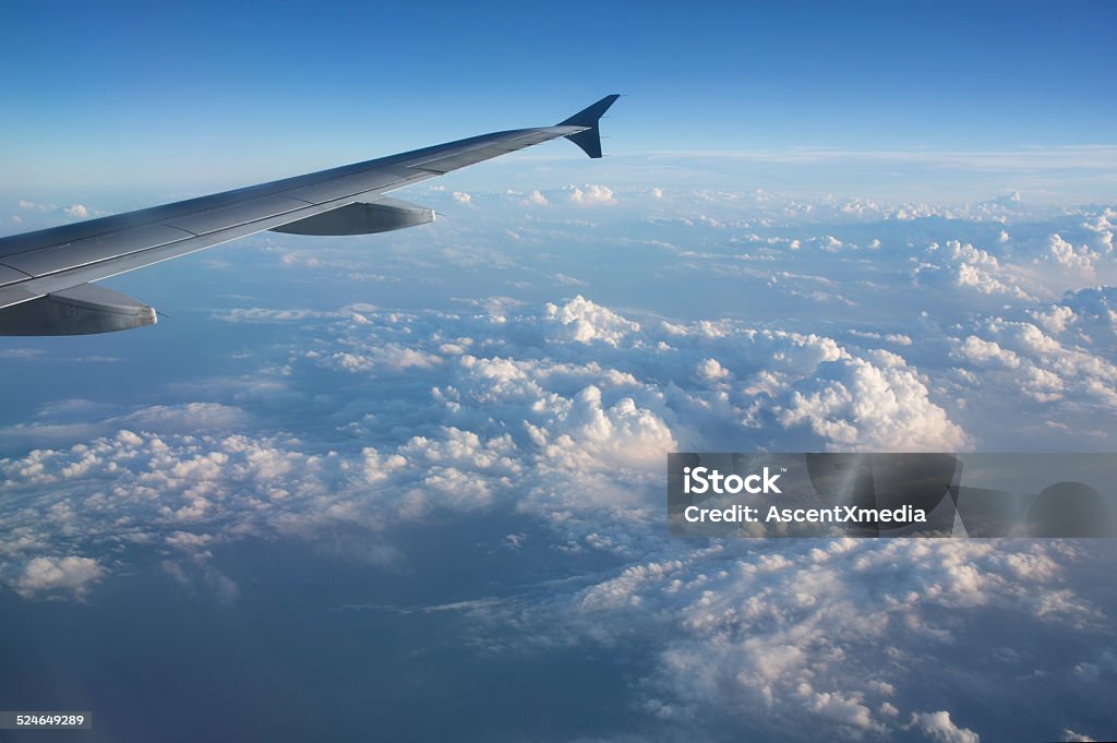 View out plane window to wing and clouds below Above Stock Photo