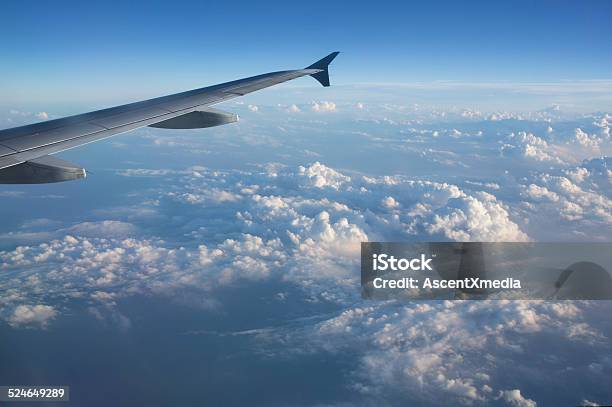 View Out Plane Window To Wing And Clouds Below Stock Photo - Download Image Now - Above, Aerial View, Aircraft Wing