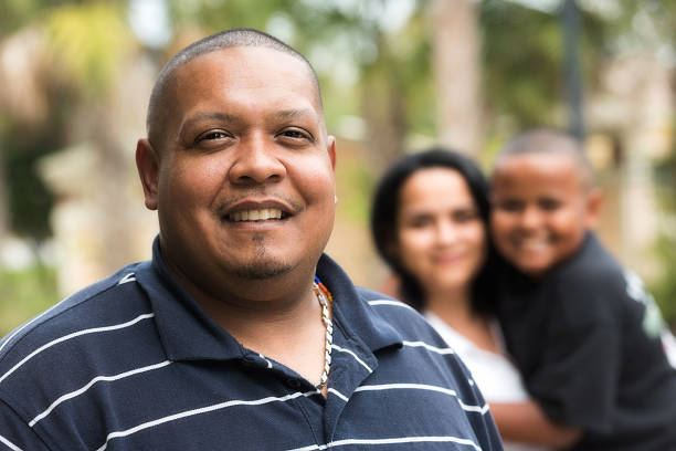 Hispanic family Hispanic man posing smiling with his wife and son in the background fat mexican man pictures stock pictures, royalty-free photos & images