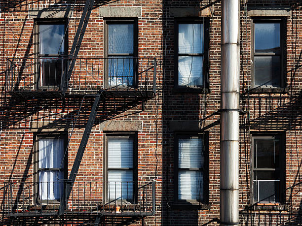 New York City house facade in neglected condition with fire escape ladders.