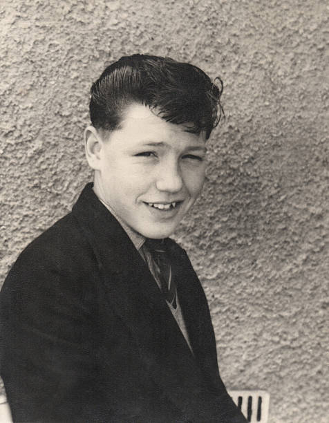 Black and white retro image, handsome 1950s teenage boy, quiff-hairstyle Old black and white photo / retro photograph showing a handsome teenage boy (15 years old) in the late 1950s, posing for the camera with a quiff hairstyle.  His hair has been combed in place with lots of wax / gel / sugar water.  He is pictured smartly dressed, wearing a jacket and tie, just after coming home from school. wax photos stock pictures, royalty-free photos & images