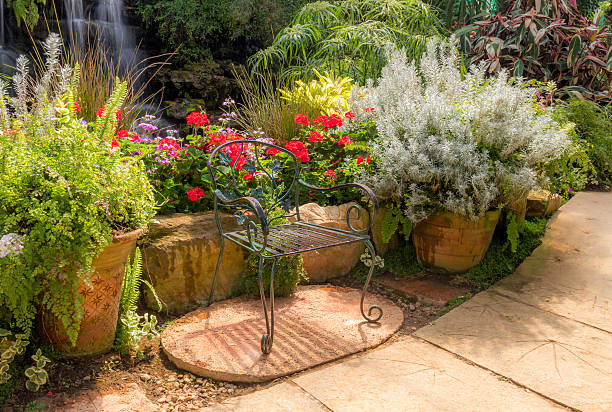 Beautiful garden setup with a table and chairs under the sun, surrounded by vibrant flowers and greenery, creating a relaxing and idyllic outdoor atmosphere perfect for leisure and tranquility