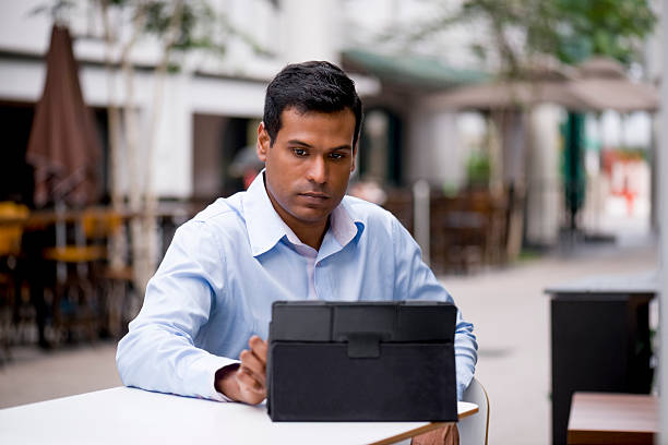 istock Indian businessman reading with a tablet at cafe 524692137