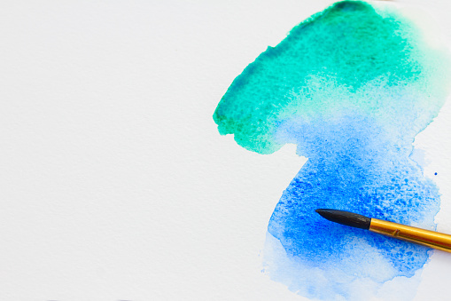 Close-up of a paintbrush with blue paint and hand drawn word PEACE. Isolated on a white background, space for copy.