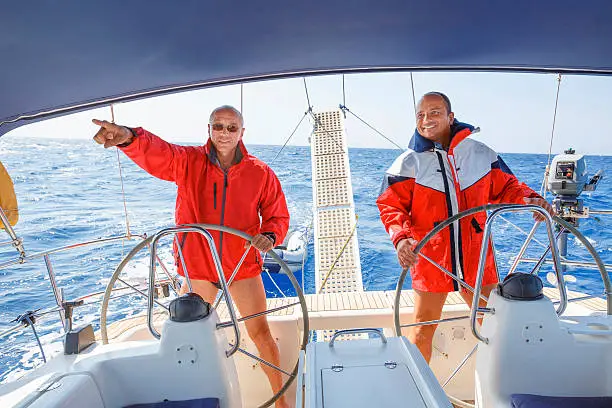 Photo of Sailing  Two men skipper on a rudder of a sailboat