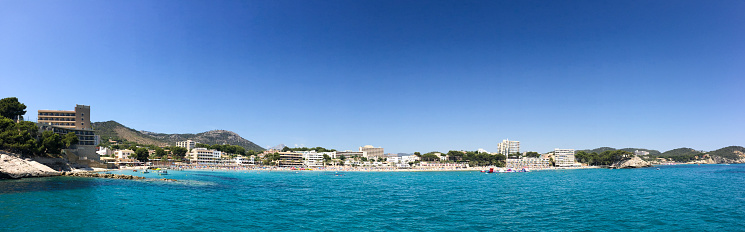 Wide panoramic wide view of various hotels and vacation destinations from empty ocean under blue sky