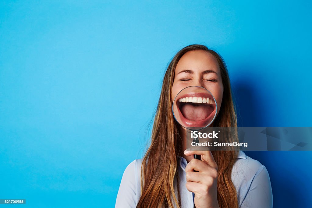 Beautiful woman laughing through magnifying glass Laughing Stock Photo