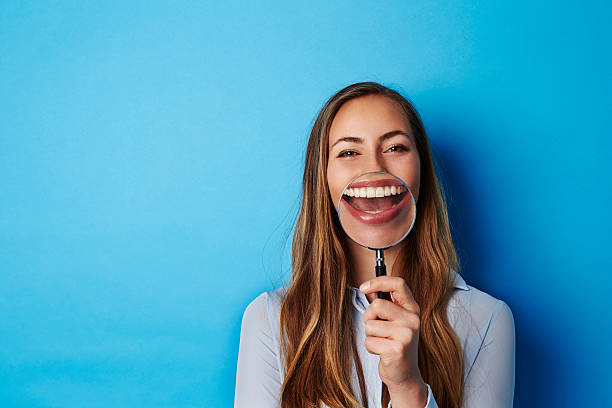 Huge smile through magnifying glass of young woman Huge smile through magnifying glass of young woman toothy smile stock pictures, royalty-free photos & images