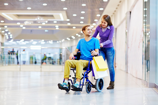 Disabled man and his girlfriend walking in shopping mall
