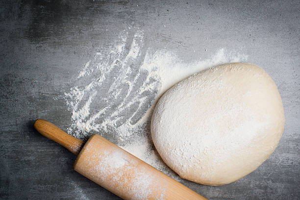 istock Dough, flour and rolling pin on a stone table 524710494