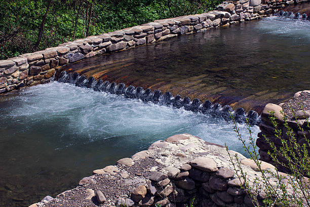 River flows through the wooden logs fenced by stone foundation