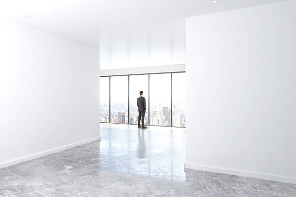 istock Businessman looking out the window in empty office with concrete 524713434