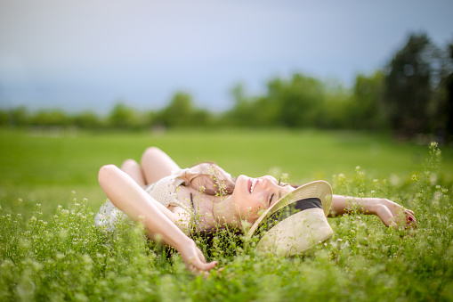 beautiful young girl lying on the grass and looking at sky