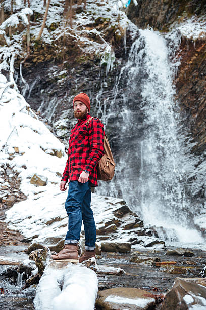 istock Serious bearded young man standing near mountain waterfall in winter 524718566
