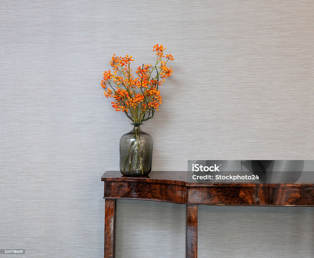 Sideboard in front of a grey wall with flower vase Sideboard in front of a grey wall with orange flower vase Flower Stock Photo