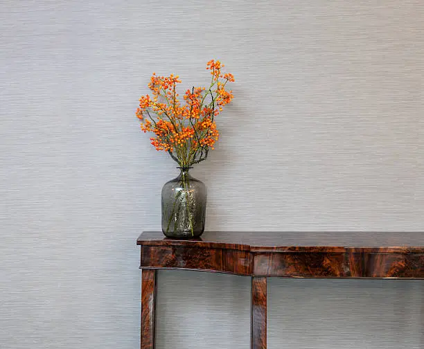 Photo of Sideboard in front of a grey wall with flower vase