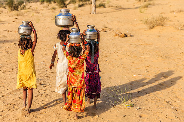 indische mädchen tragen von wasser auf den kopf gut - poverty india child little girls stock-fotos und bilder