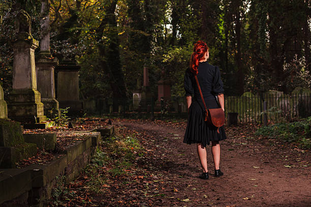 istock Young redhead woman standing in cemetery 524721999