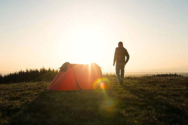 istock Wild Camping, Man with red tent in remote countryside. 524722854