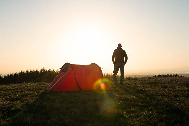 istock Wild Camping, Man with red tent in remote countryside. 524723014