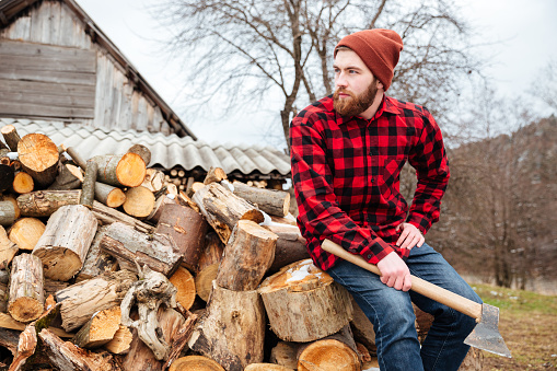 Lumberjack with axe resting outdoors and looking away