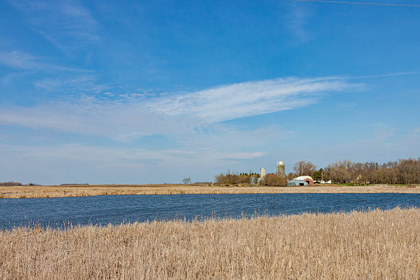 A farm beyond a pond on the open prairie