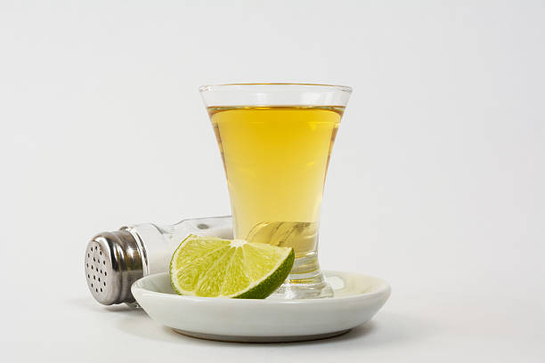 Tasty tequila served in glasses with lime green slices on top on a white background - Close-up