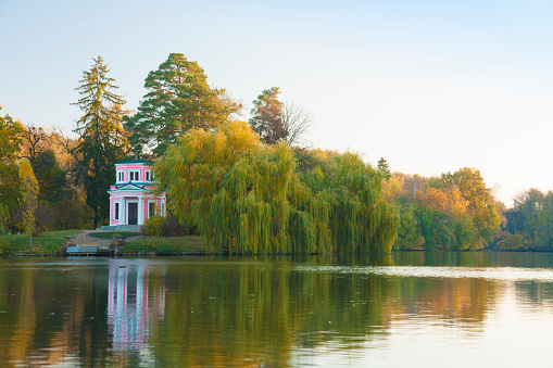 Ancient pink pavilion in autumn park on a lake