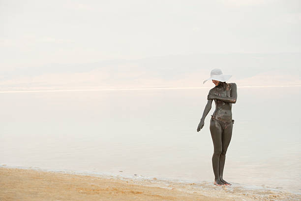 mujer con la aplicación de mineral intensos en mud del mar muerto. - dead sea fotografías e imágenes de stock