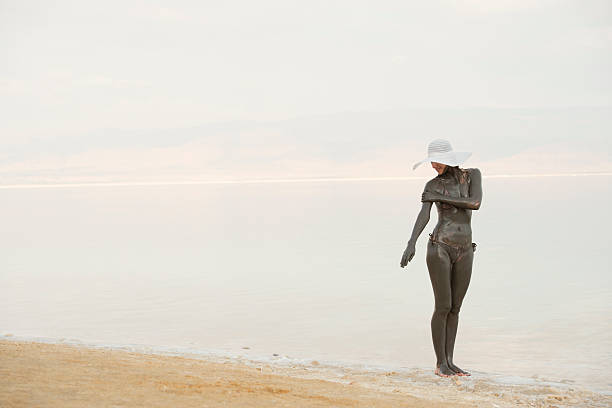 женщина с применением богатые минералами грязи из мертвого моря. - swimwear people fashion model leisure activity стоковые фото и изображения