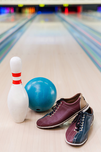 Close-up of bowling shoes, blue ball and pin lying on bowling alley