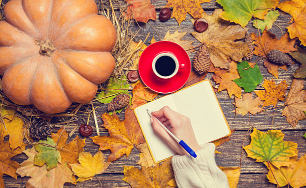 istock Female hand wrinig something in notebook on autumn background. 524746247