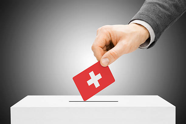 Male inserting flag into ballot box - Switzerland stock photo