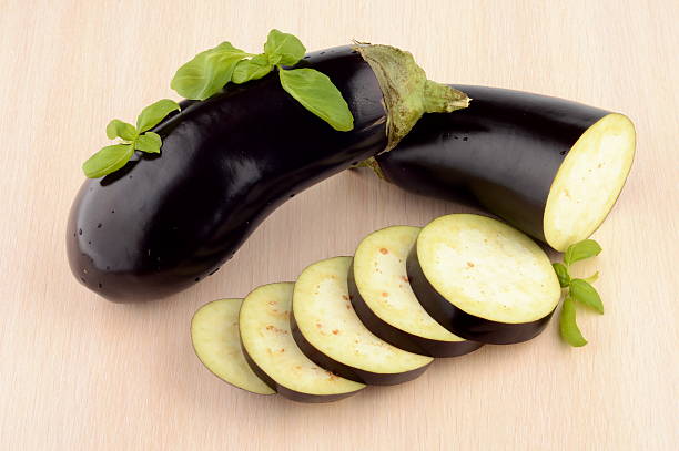 istock Sliced aubergine, eggplant with basil leaves on bright wooden table 524820231