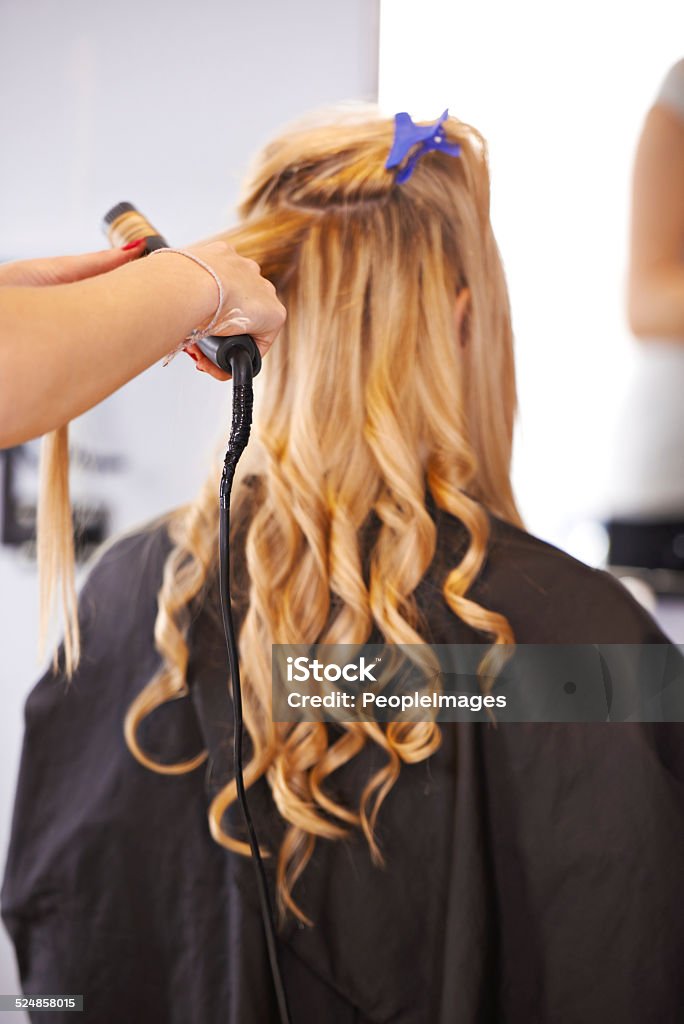 Her hair is in perfect hands A blonde woman getting her hair curled in a salon Curled Up Stock Photo