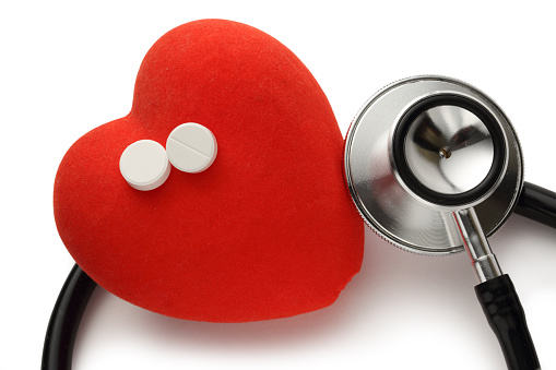 Green stethoscope and red heart isolated on wooden white background