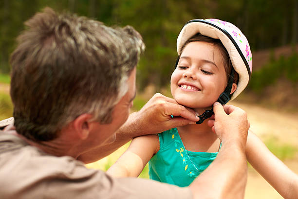 He's the best dad ever Shot of a father adjusting his daughter's helmet cycling helmet photos stock pictures, royalty-free photos & images