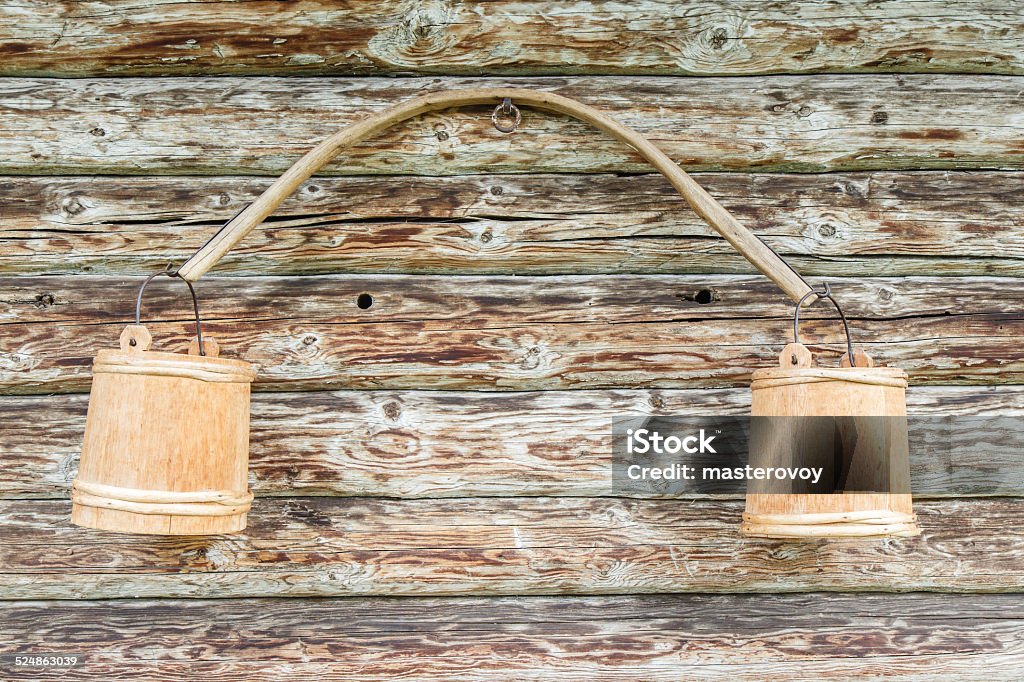 Carrying pole with buckets Carrying pole with buckets against a wooden wall Bucket Stock Photo