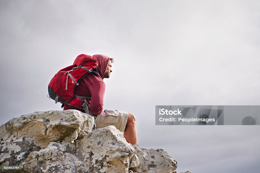 Enjoying the fruits of his labour Shot of a young man enjoying a hike through the mountains Activity Stock Photo