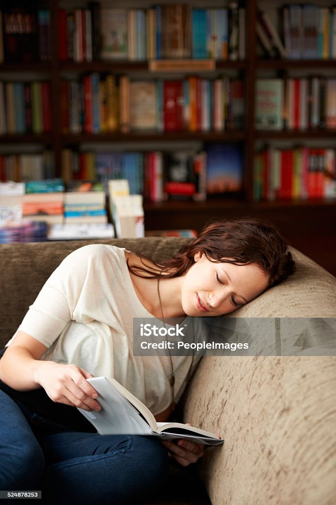 Spirited away with words An attractive young woman relaxing on a sofa with a book Sleeping Stock Photo